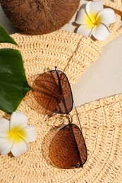 Photo of Flat lay composition with stylish sunglasses and wicker bag on sand