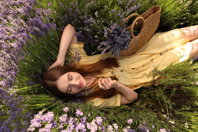 Photo of Young woman lying in lavender field on summer day, top view