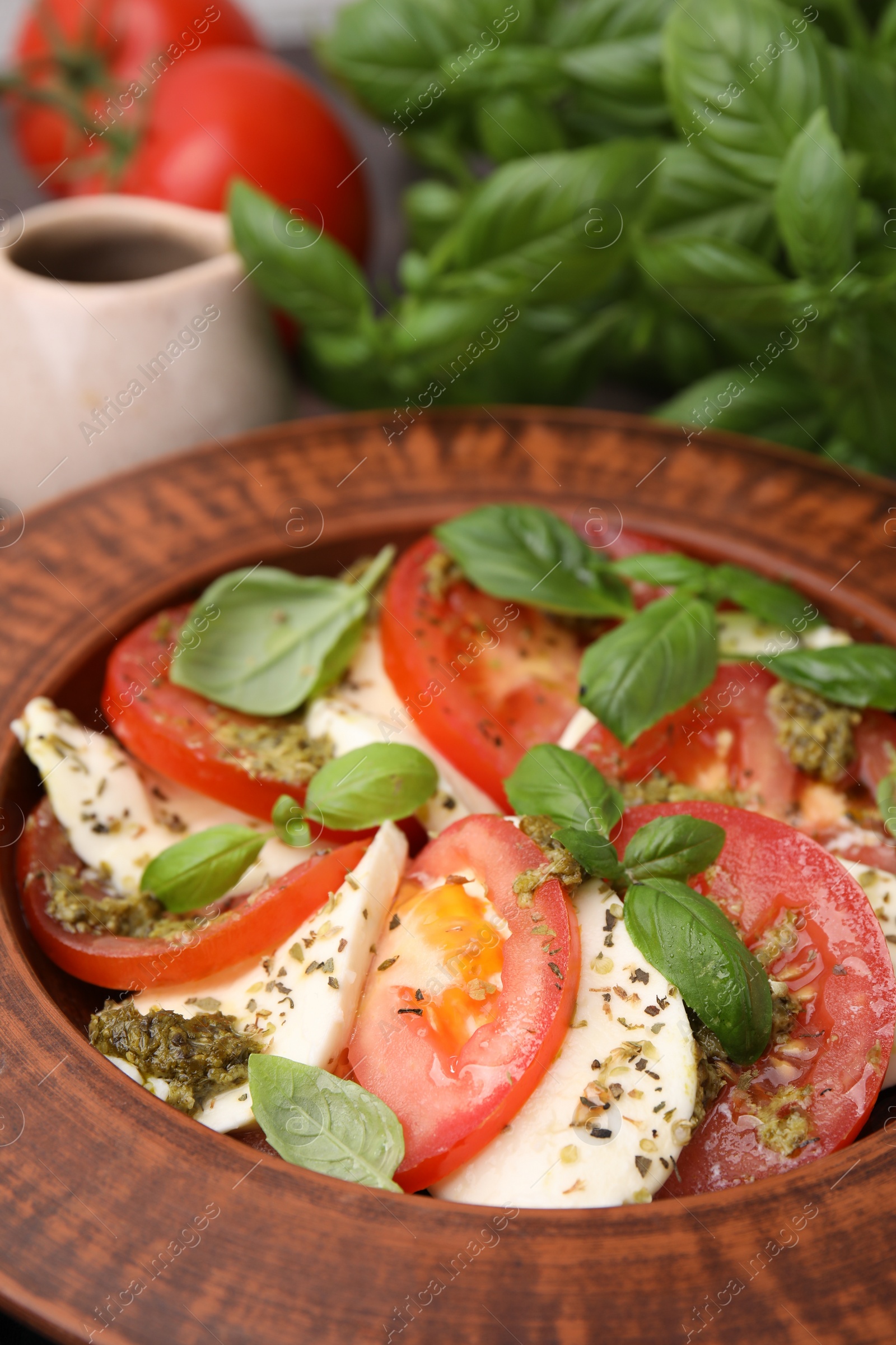 Photo of Plate of delicious Caprese salad with pesto sauce on table, closeup