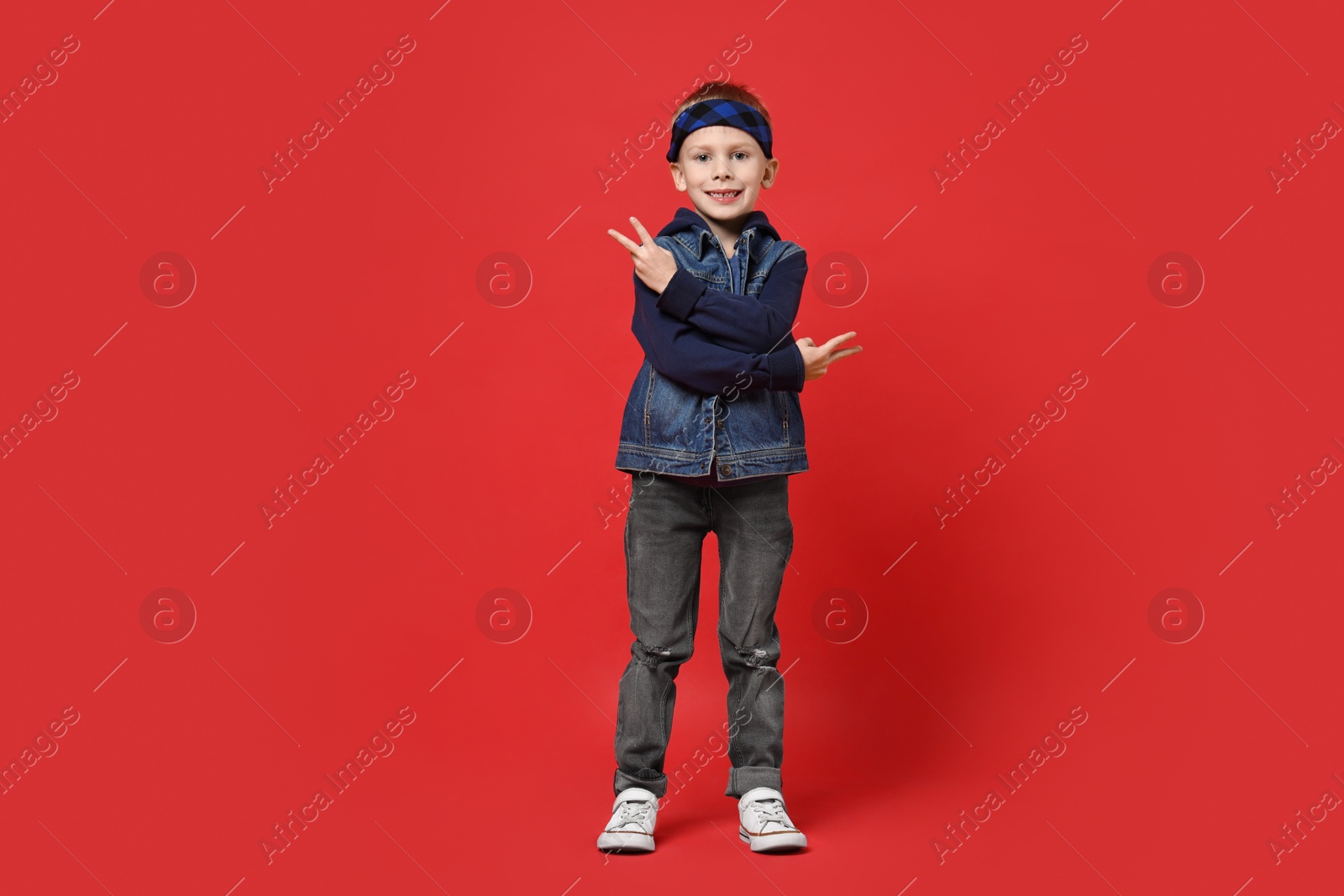 Photo of Happy little boy dancing on red background