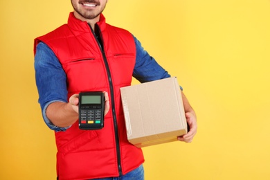 Photo of Male courier with parcel and payment terminal on color background, closeup. Space for text