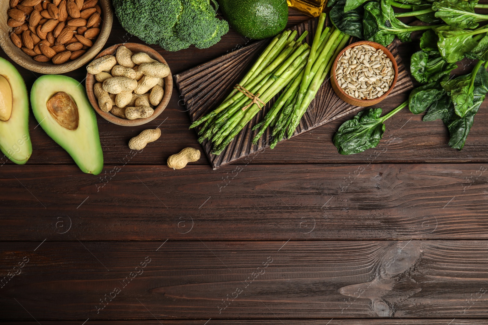 Photo of Different products rich in vitamin E on wooden table, flat lay. Space for text