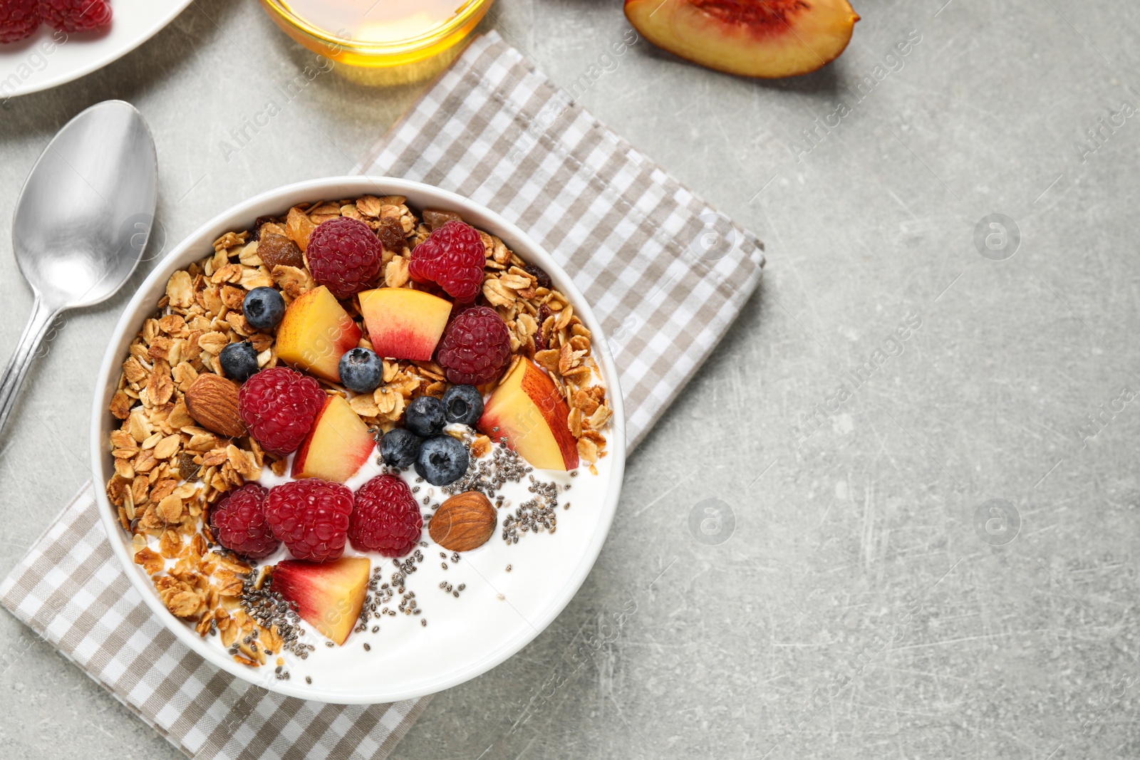 Photo of Healthy homemade granola with yogurt served on grey table, flat lay. Space for text