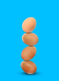 Image of Stacked fresh chicken eggs against light blue background