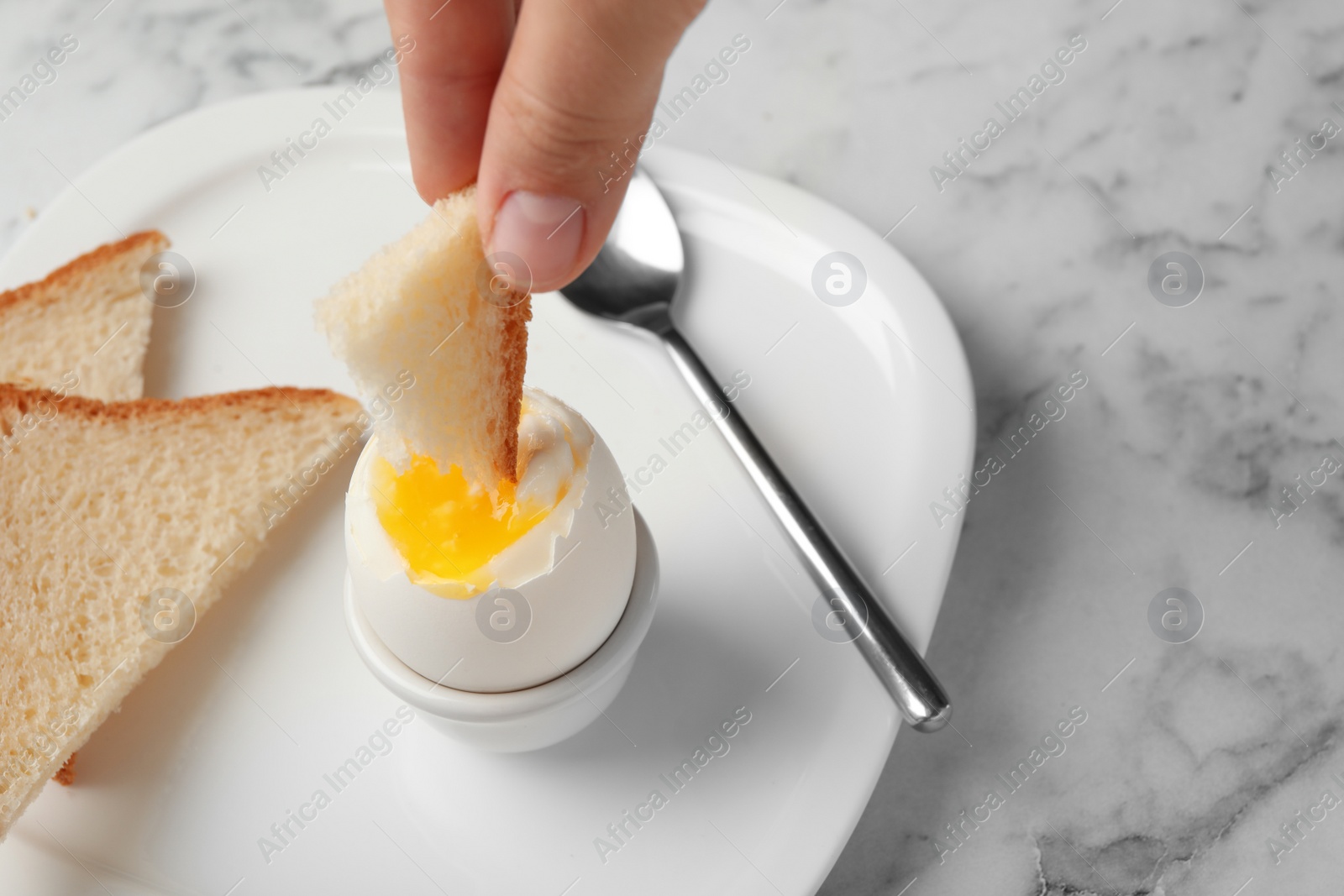 Photo of Woman dipping bread into soft boiled egg on table, closeup. Space for text