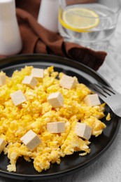 Plate with delicious scrambled eggs and tofu on white table, closeup