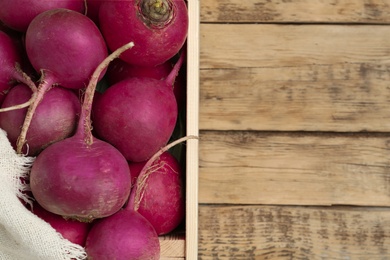 Photo of Crate with red turnips on wooden table, top view. Space for text