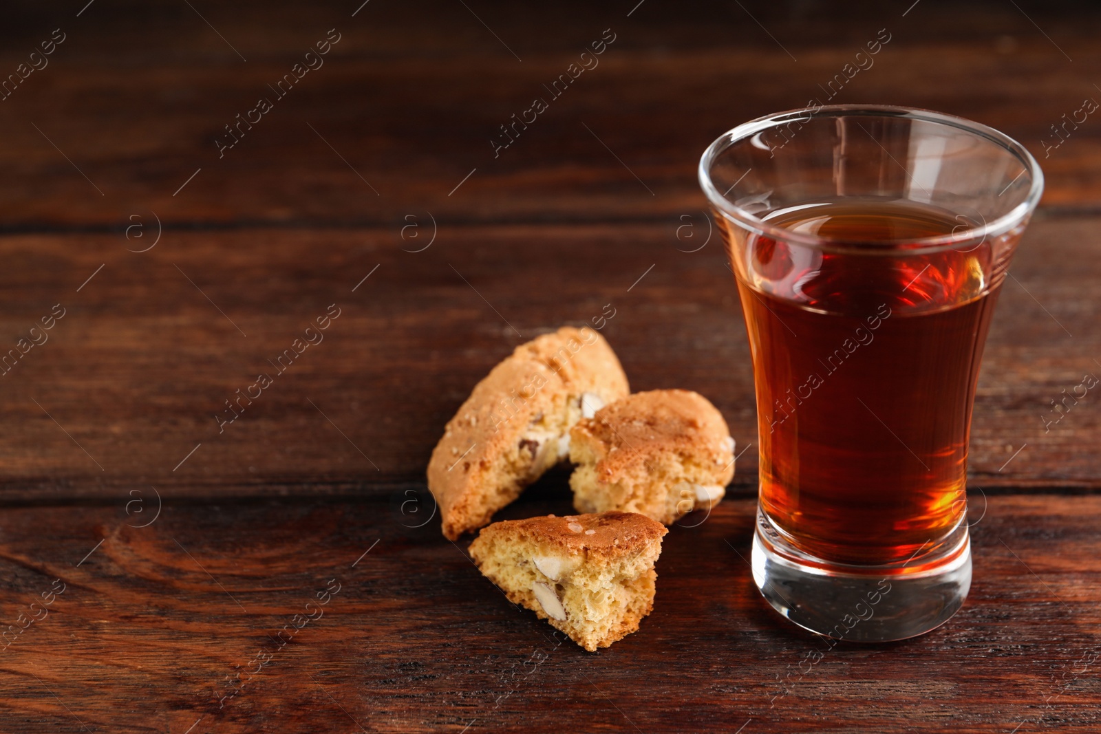 Photo of Tasty cantucci and glass of liqueur on wooden table, space for text. Traditional Italian almond biscuits