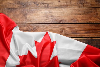 Photo of Flag of Canada on wooden background, top view. Space for text