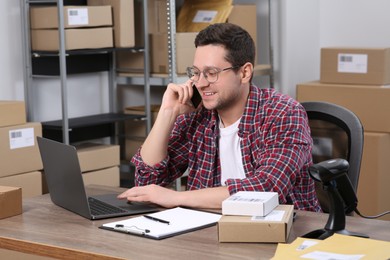 Photo of Seller talking on phone while working in office. Online store