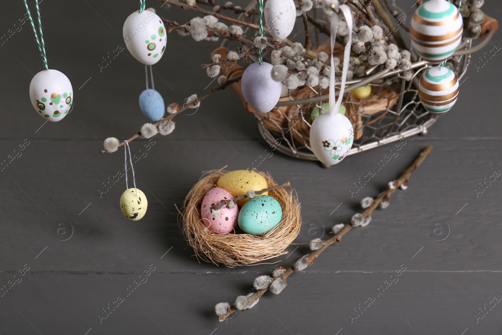 Photo of Beautiful willow branches with painted eggs and Easter decor on light grey wooden table, above view
