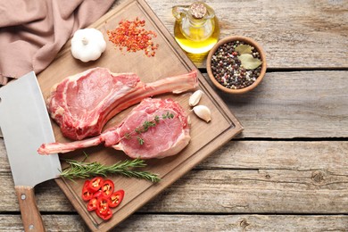 Photo of Fresh tomahawk beef cuts, butcher knife and spices on wooden table, top view. Space for text
