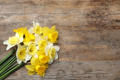 Photo of Bouquet of daffodils on wooden background, top view with space for text. Fresh spring flowers