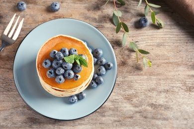 Photo of Plate with pancakes and berries on wooden background, top view