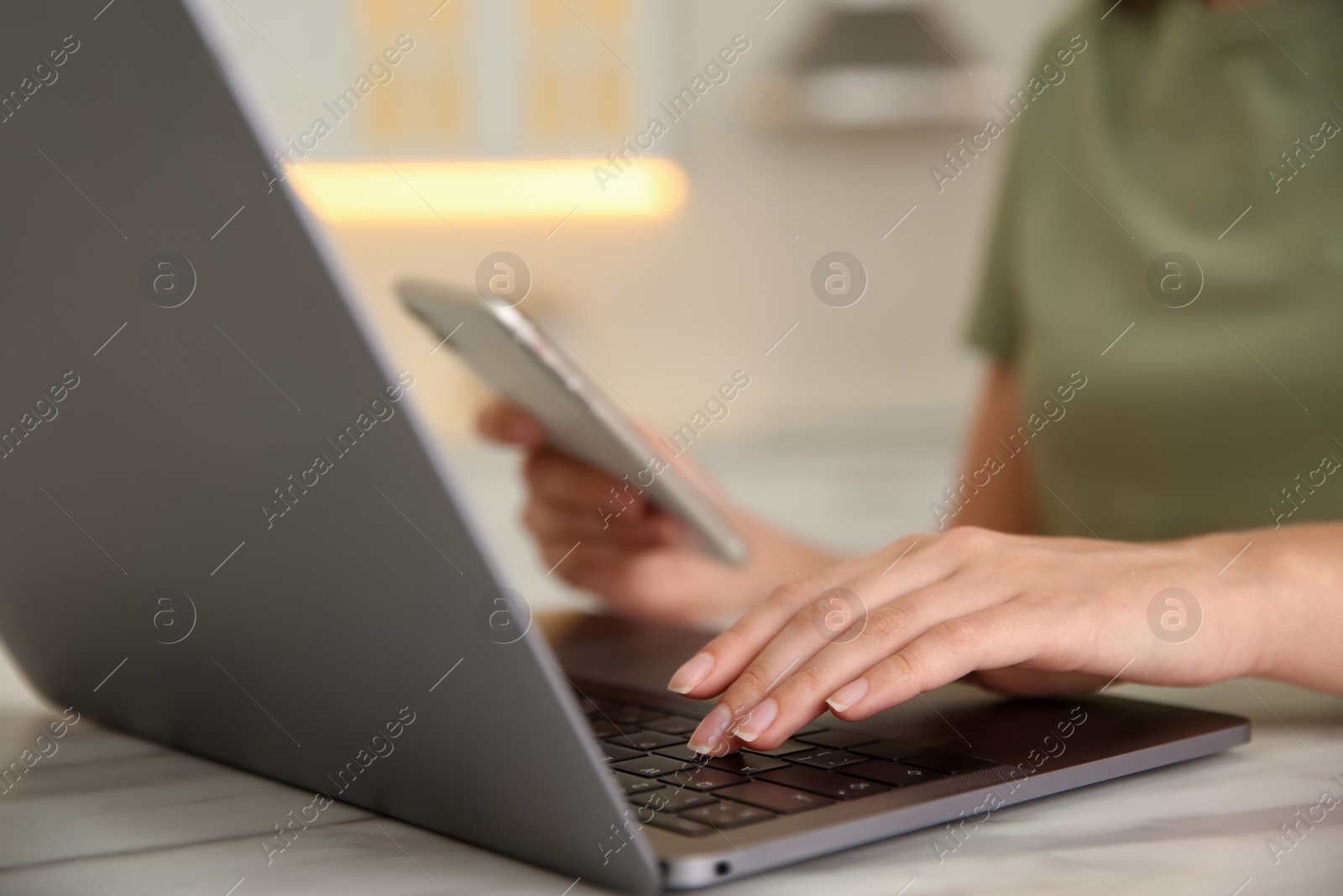 Photo of Woman working with modern laptop at marble table, closeup