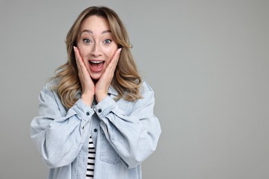 Portrait of happy surprised woman on grey background. Space for text