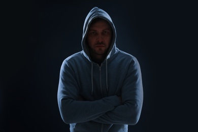 Photo of Mysterious man in hoodie on dark background. Dangerous criminal