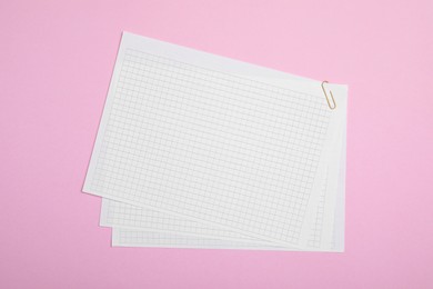 Sheets of paper with clip on pink background, top view