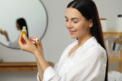 Photo of Young woman applying essential oil on wrist indoors