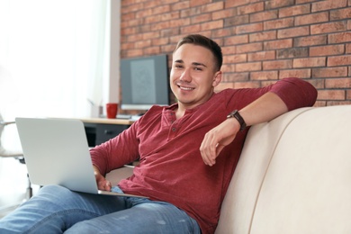 Photo of Young man working with laptop in home office