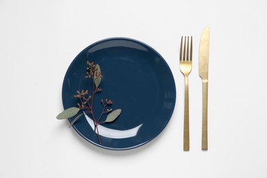 Stylish setting with cutlery and eucalyptus leaves on white background, top view
