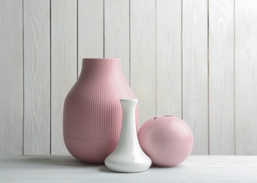 Stylish ceramic vases on white wooden table