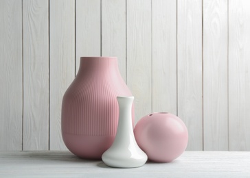 Photo of Stylish ceramic vases on white wooden table