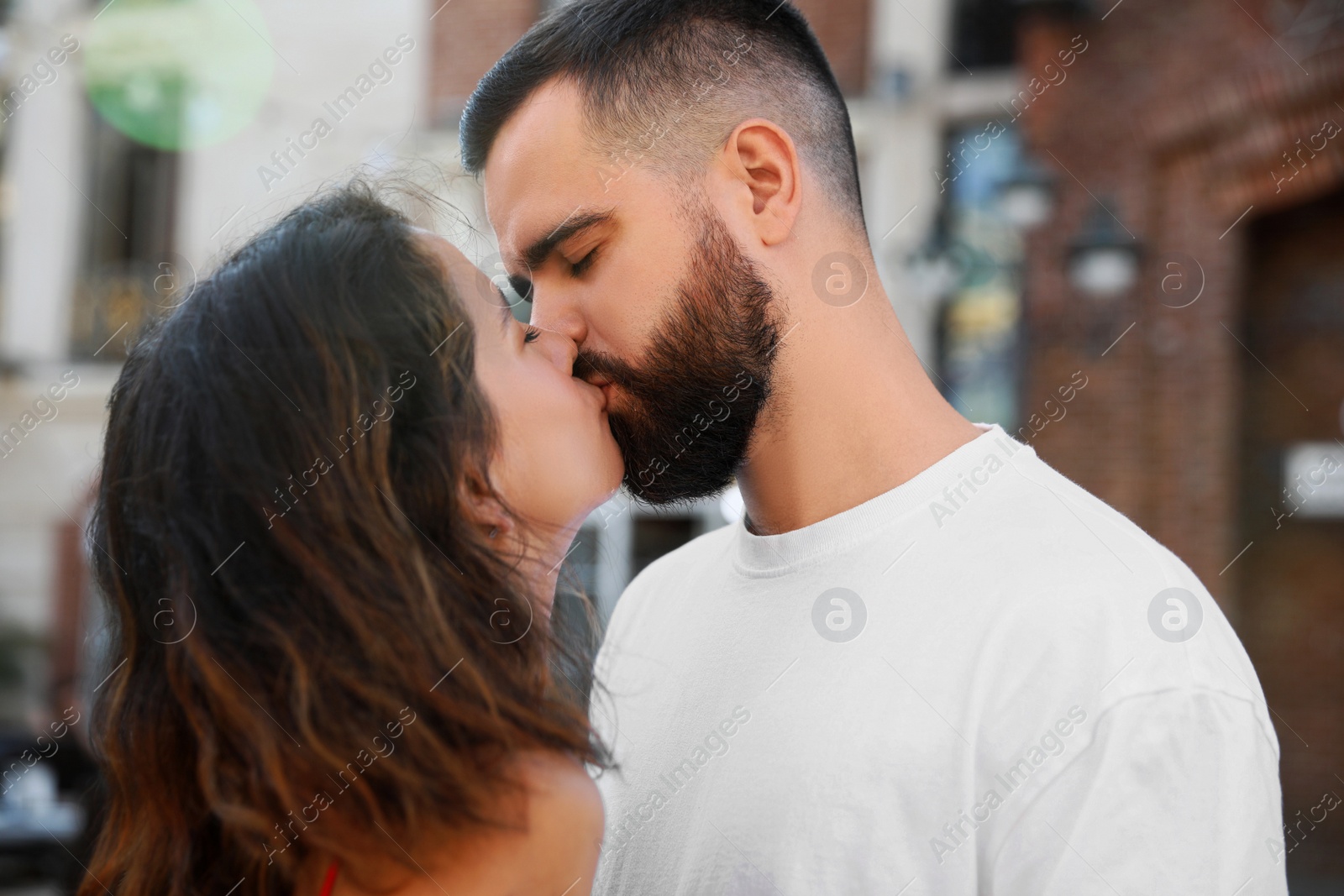 Photo of Happy young couple kissing on city street