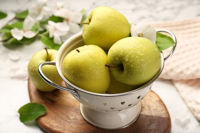 Colander with fresh wet apples on white table, closeup