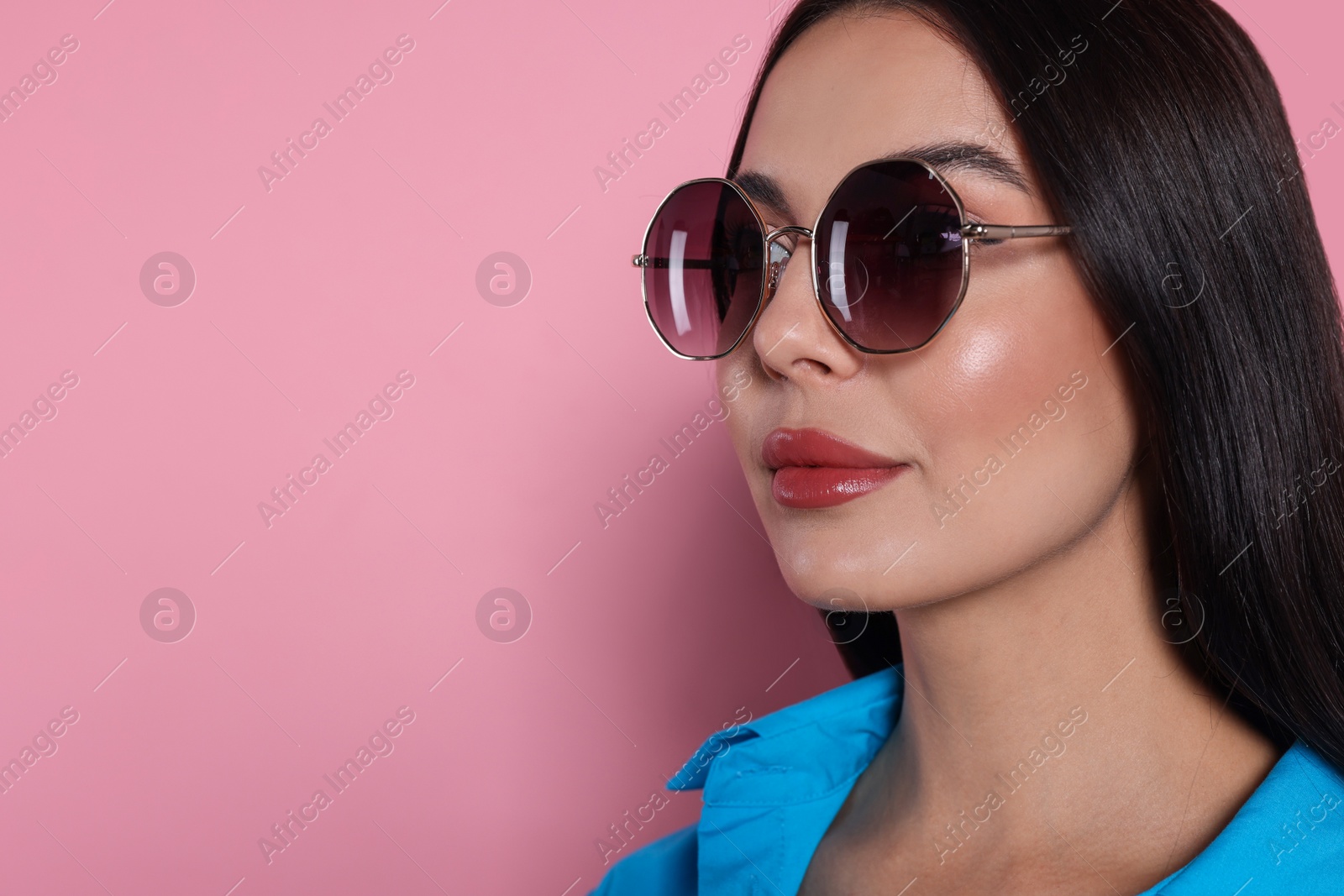 Photo of Attractive serious woman in fashionable sunglasses against pink background, closeup. Space for text