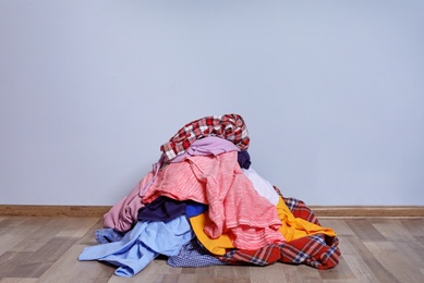 Photo of Pile of dirty clothes on floor near color wall