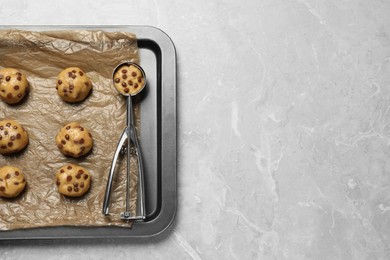 Photo of Tray with uncooked chocolate chip cookies on light grey table, top view. Space for text