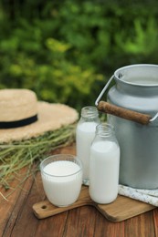Photo of Fresh milk on wooden table outdoors. Space for text