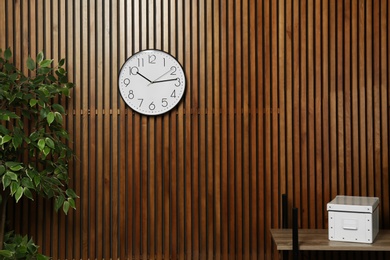 Photo of Room interior with clock and space for text on wooden wall. Time management