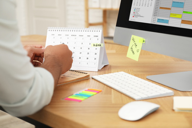 Photo of Man working with calendar at table in office, closeup