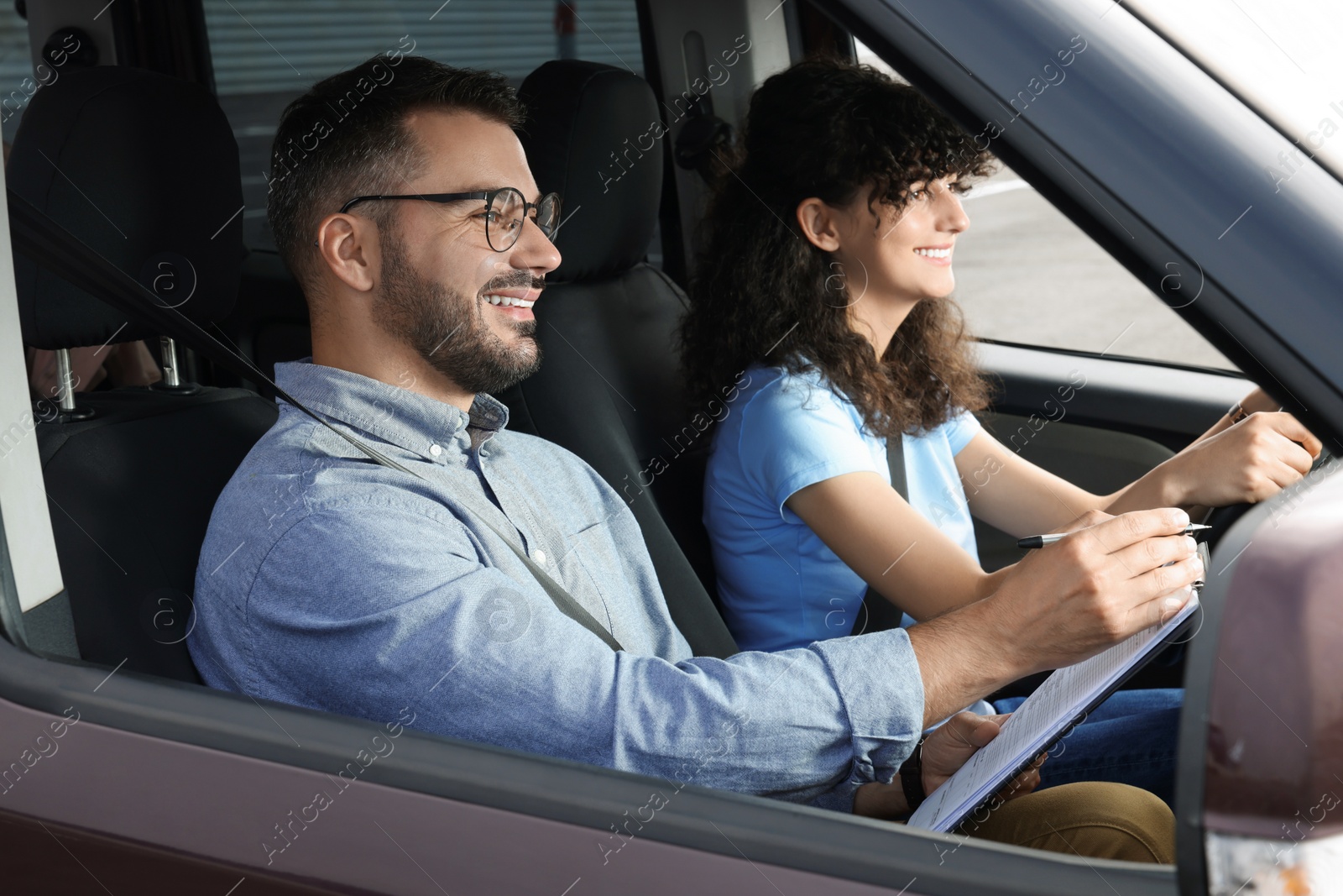 Photo of Driving school. Happy student passing driving test with examiner in car