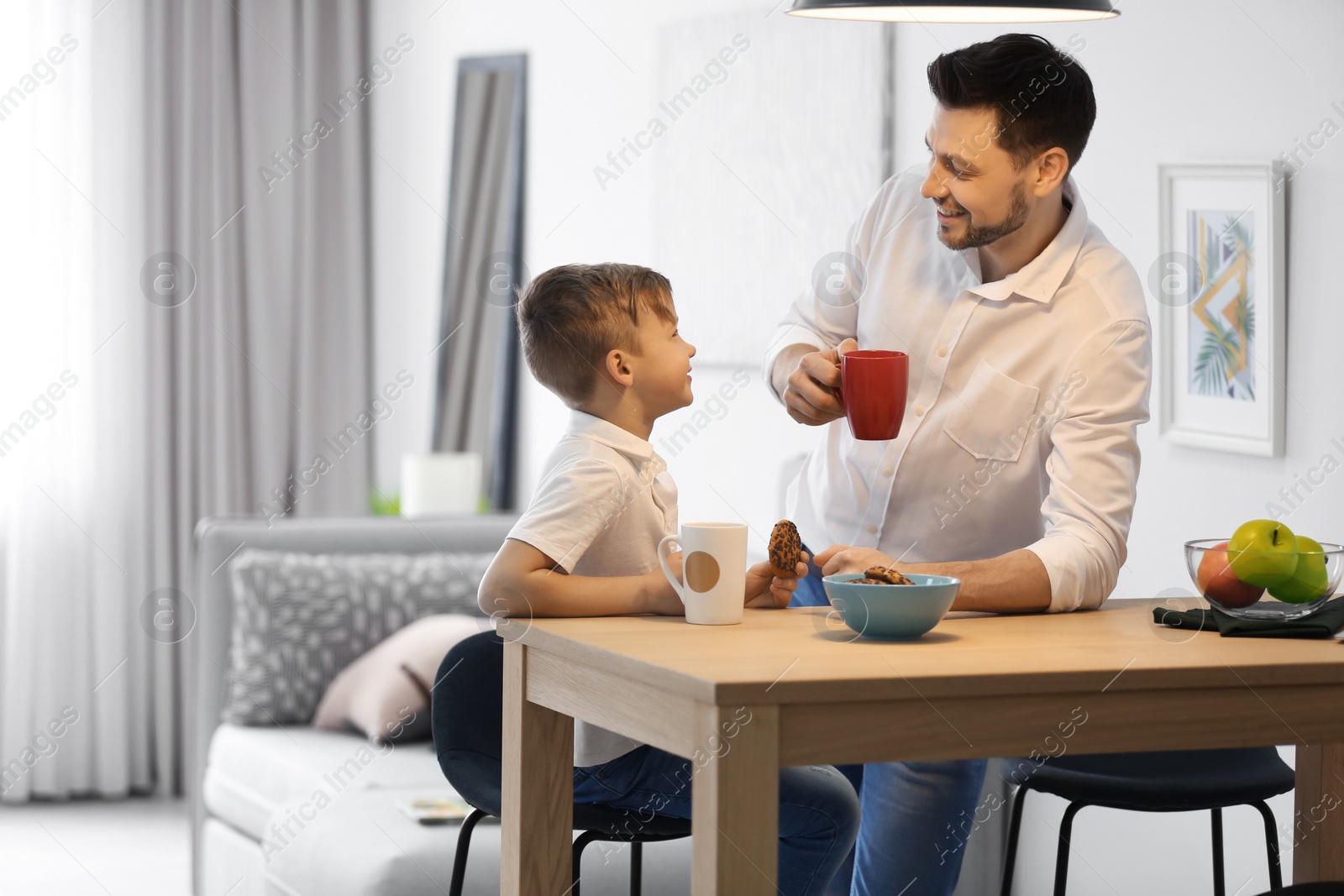 Photo of Little boy and his dad having breakfast at home