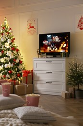 Image of Stylish living room interior with TV set, Christmas tree and gifts