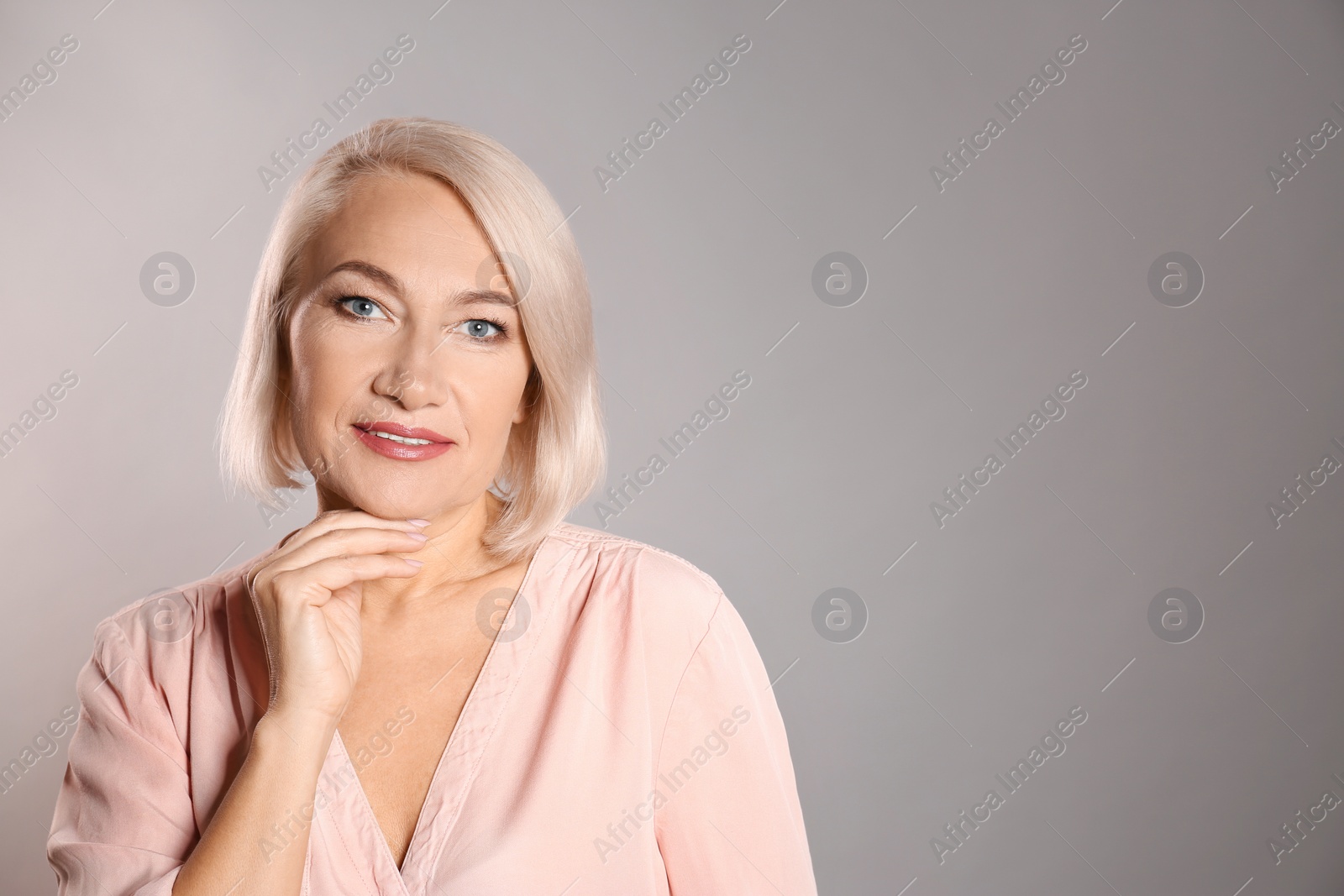 Photo of Portrait of charming mature woman with healthy beautiful face skin and natural makeup on grey background, space for text
