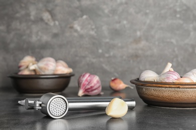 Photo of Garlic press and clove on table. Kitchen utensil