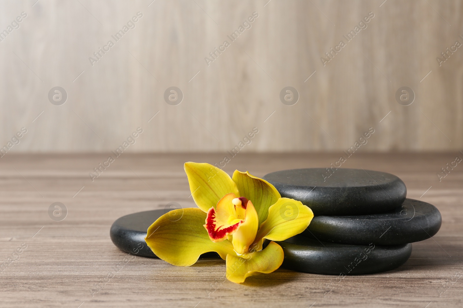 Photo of Spa stones and flower on wooden table, space for text