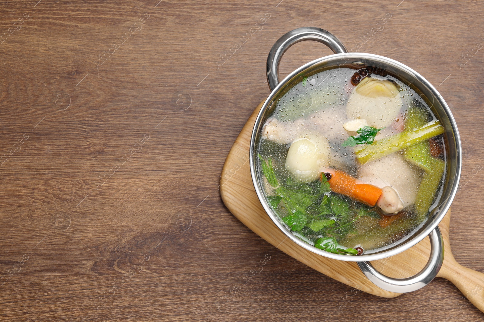 Photo of Pot with tasty bouillon on wooden table, top view. Space for text