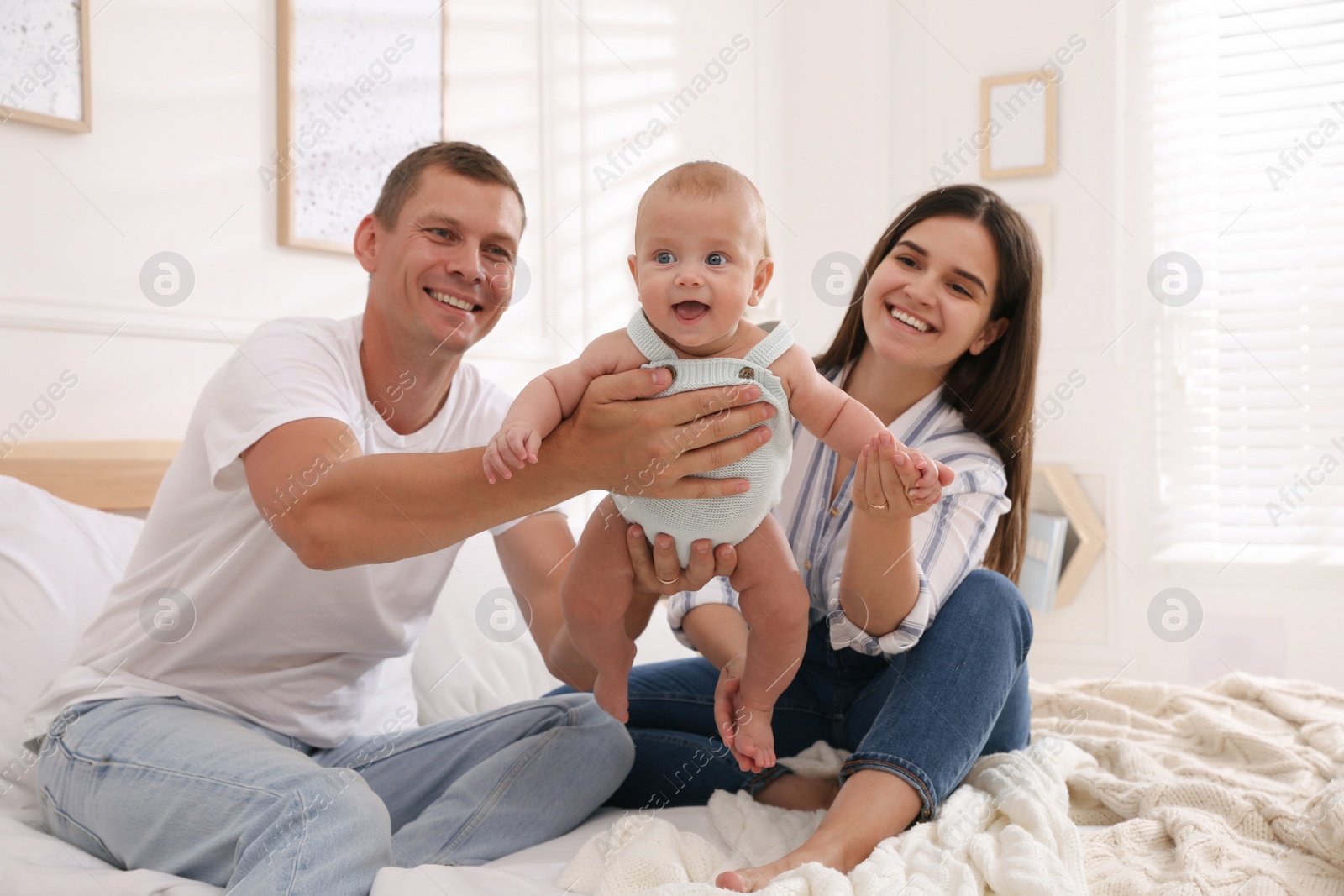 Photo of Happy family with their cute baby on bed at home