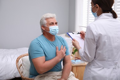 Doctor examining senior man with protective mask at nursing home