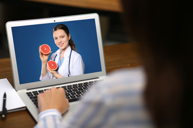 Woman using laptop for online consultation with nutritionist via video chat, closeup