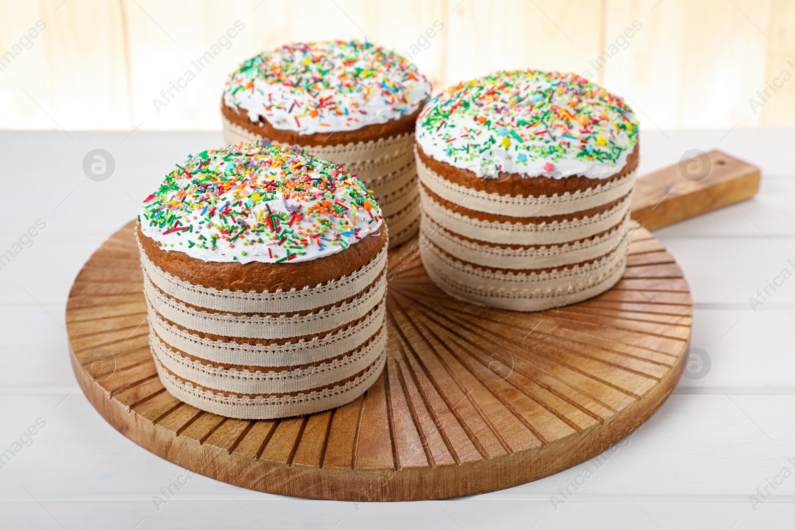 Photo of Traditional Easter cakes with sprinkles on white wooden table