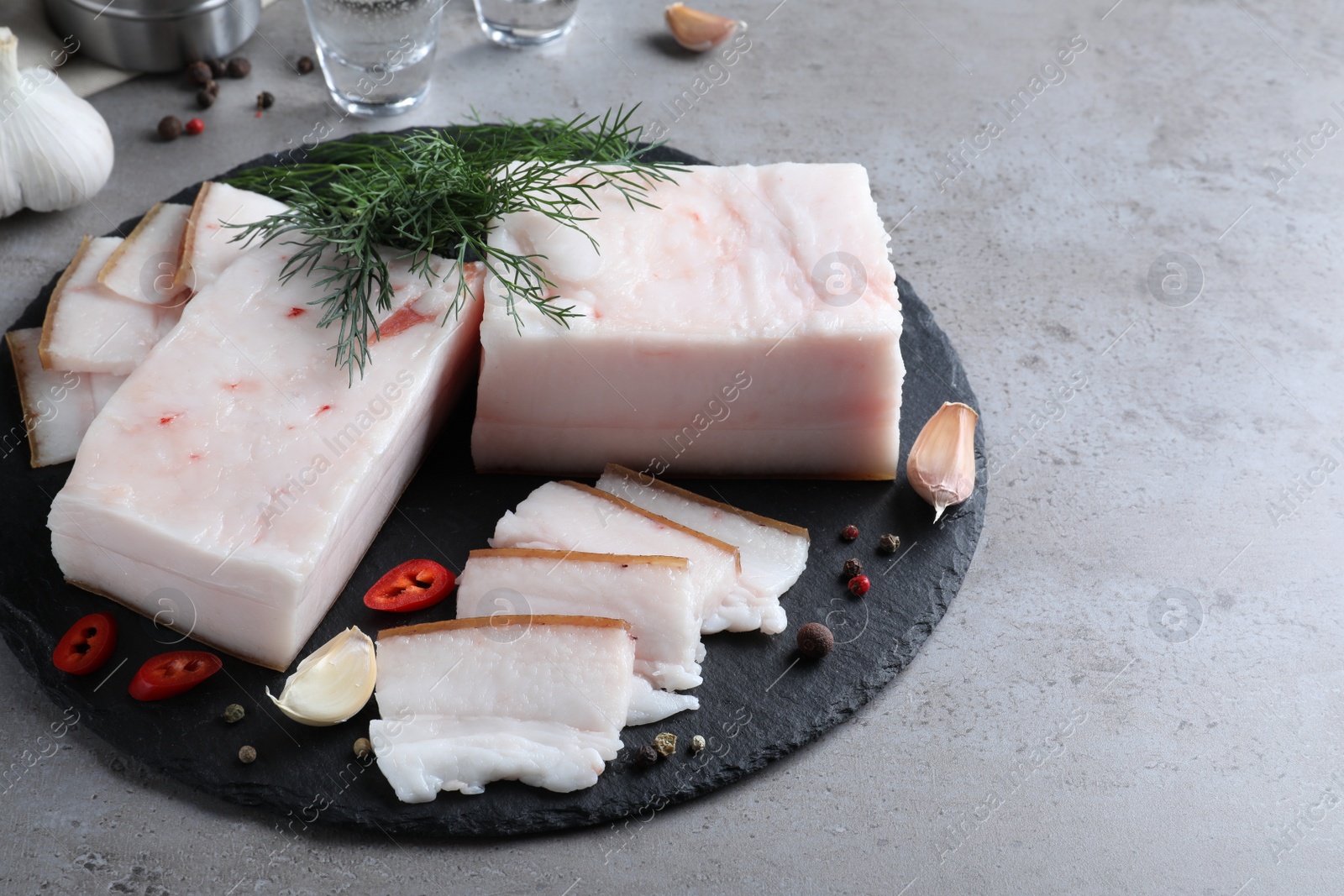 Photo of Pork fatback with spices served on grey table. Space for text