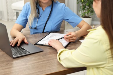 Photo of Doctor with results of laboratory test consulting pregnant patient in clinic, closeup