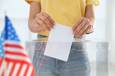 Woman putting ballot paper into box at polling station, closeup
