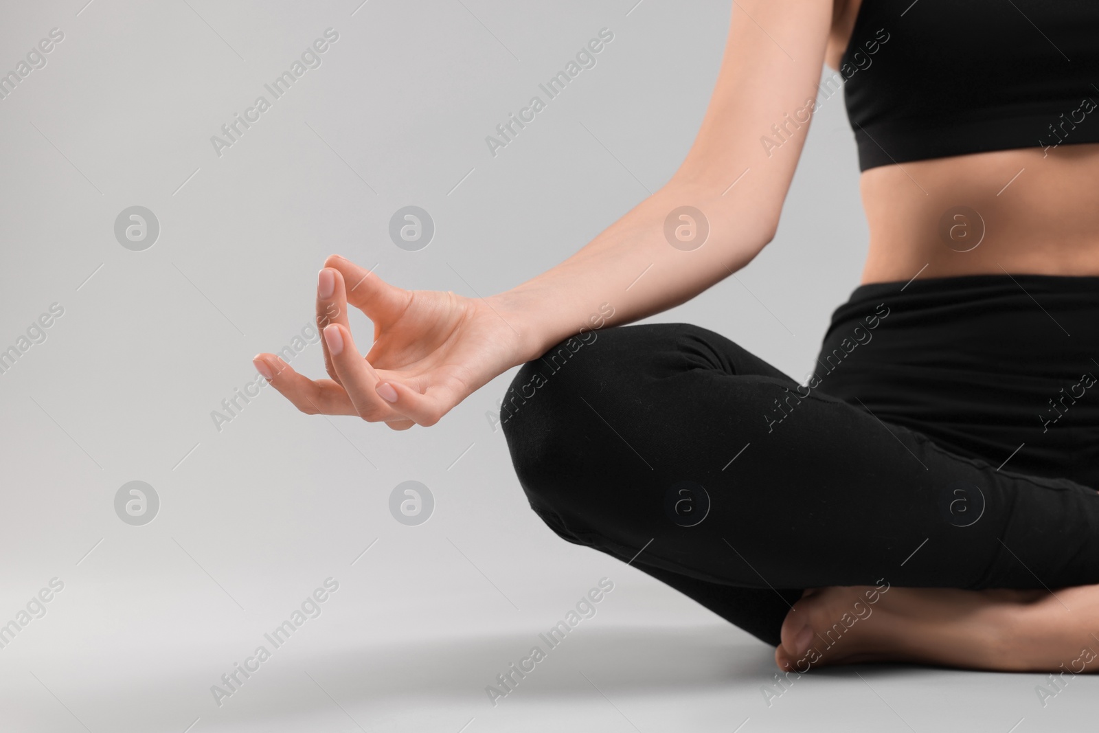 Photo of Woman practicing yoga on grey background, closeup and space for text. Lotus pose